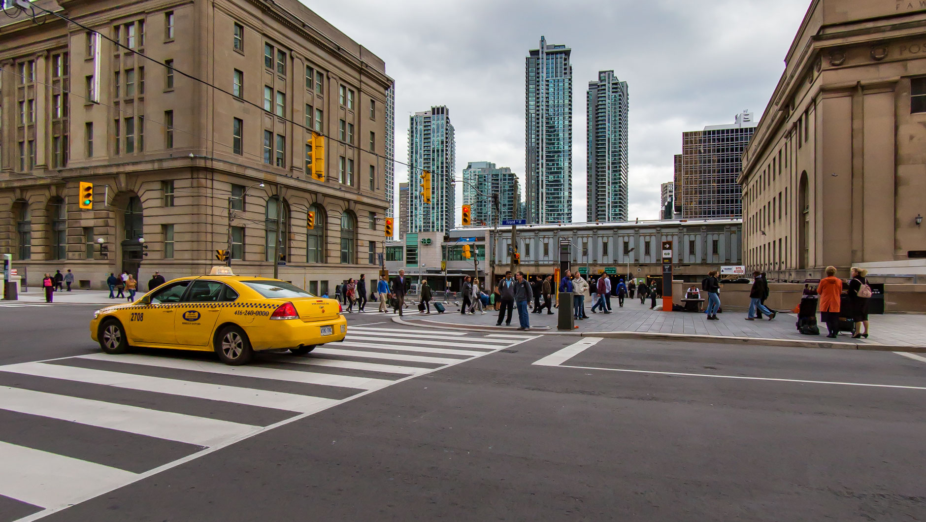 Front Street in Toronto (Kanada). Gelbes Taxi und Hochhäuser. Union Station.