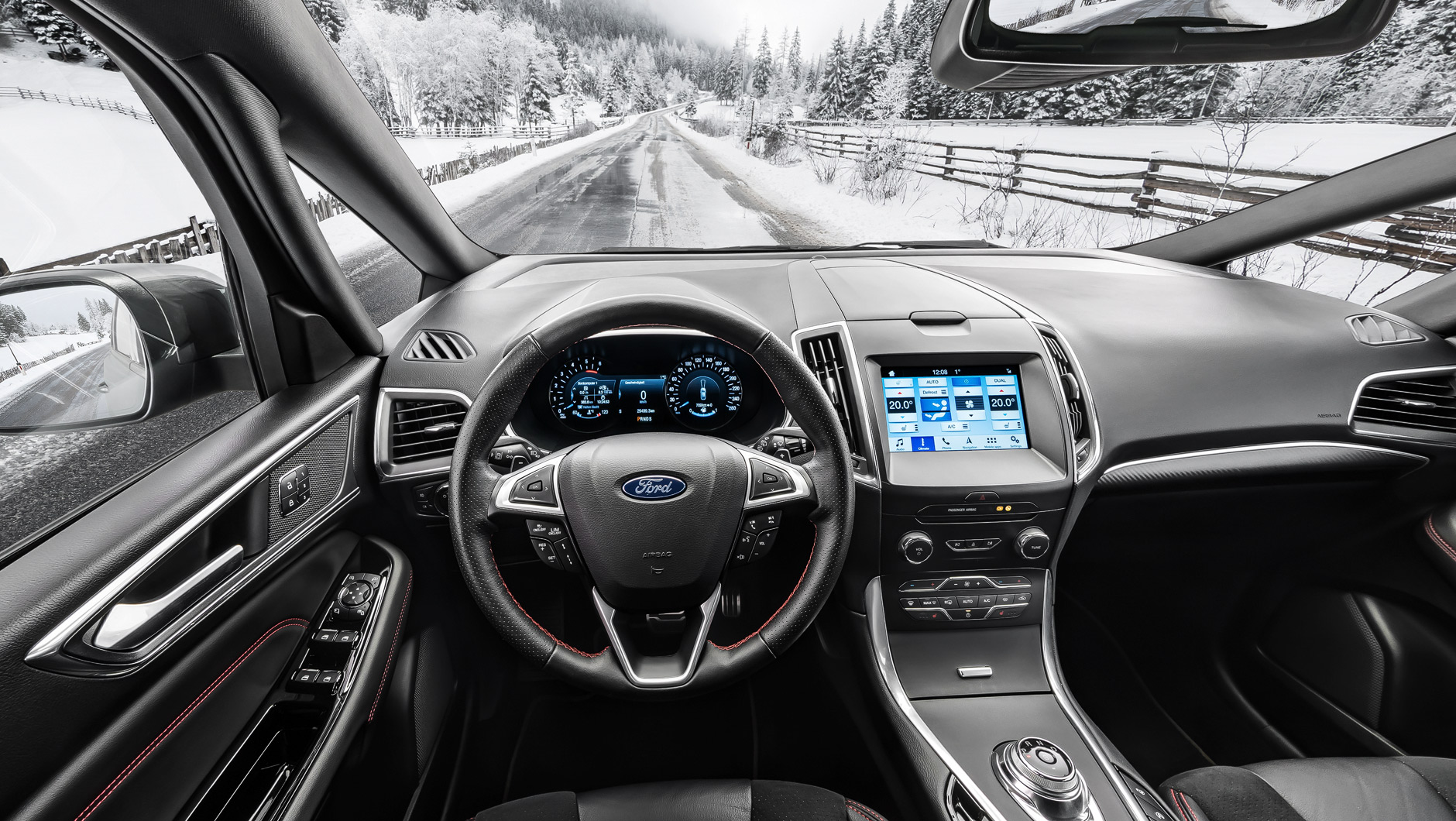 Autoinnenraum / Interior eines Ford S-MAX ST-Line. Foto aufgenommen aus der Perspektive des Fahrers. Das Auto steht auf einer nassen Straße in den verschneiten Alpen.